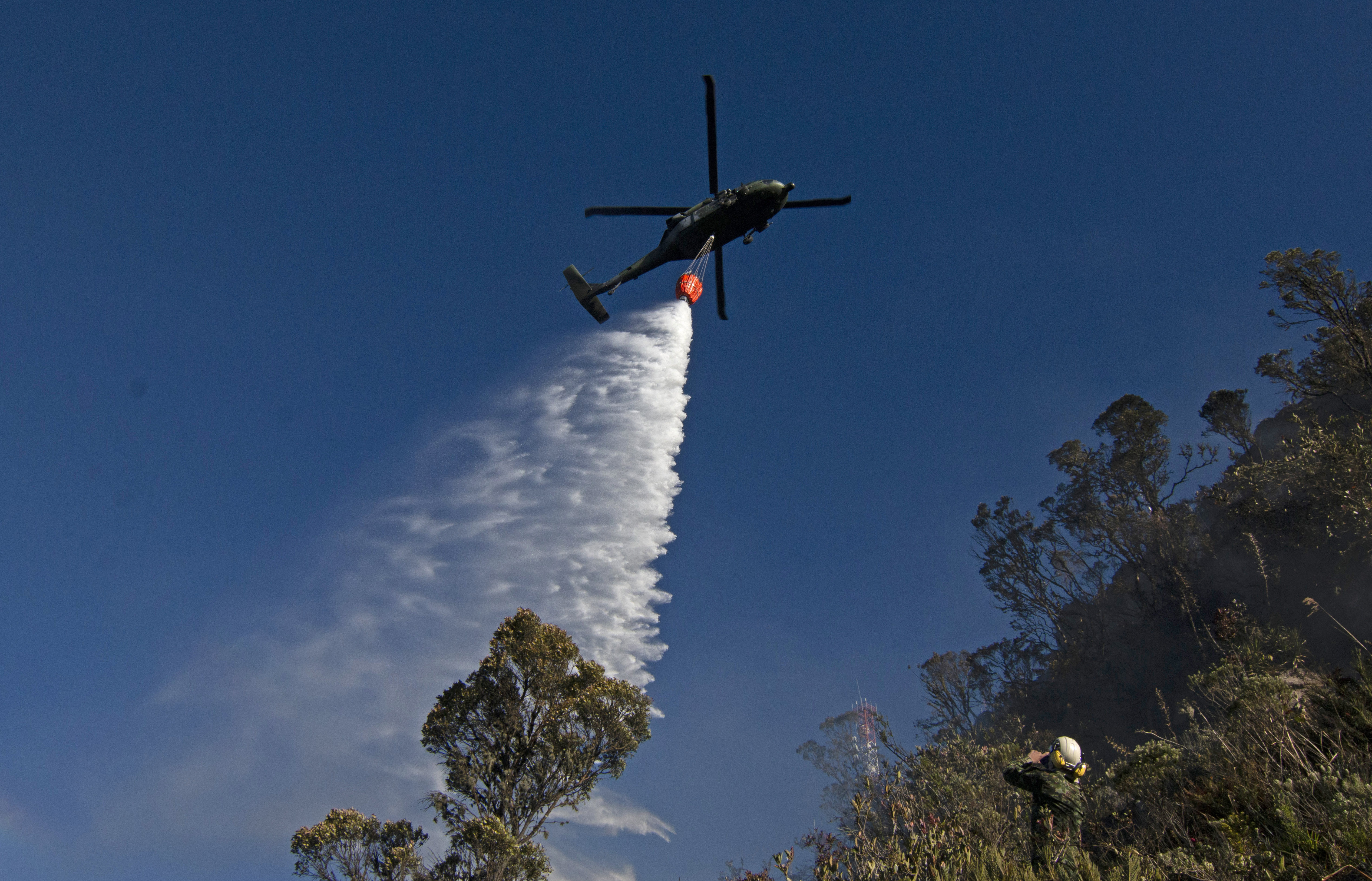 AME1862. SANTURBÁN (COLOMBIA), 24/01/2024.- Un helicóptero militar participa hoy en labores de extinción de incendios forestales cerca al páramo de Berlín, en el nudo de Santurbán en Santander (Colombia). Decenas de hectáreas de vegetación de alta montaña han sido consumidas por un incendio en el páramo de Berlín, crucial para el abastecimiento de agua potable del noreste de Colombia, informaron este miércoles las autoridades. El páramo de Berlín hace parte del sistema de páramos de Santurbán, una de las principales reservas de agua potable del país y está incluido entre los Parques Nacionales. EFE/ Mario Caicedo