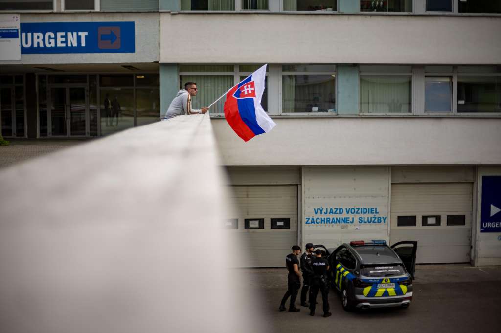 Banska Bystrica (Slovakia (slovak Republic)), 16/05/2024.- A man waves Slovak national flag as police car is parked outside the F. D. Roosevelt University Hospital, where Slovak Prime Minister Robert Fico is being treated after being shot on 15 May, in Banska Bystrica, Slovakia, 16 May 2024. The Slovak government office on 15 May confirmed there had been an assassination attempt on Prime Minister Robert Fico following a meeting in the town of Handlova. According to Slovak Defence Minister Kalinak on 16 May, Fico was in stable but serious condition after surgery. (Eslovaquia) EFE/EPA/MARTIN DIVISEK
