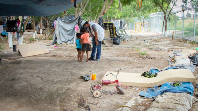 Un promotor de salud de MSF platica con un par de niñas que esperan junto con sus familias la reapertura de la frontera. En agosto se estimó que hasta 1,600 personas vivían en el campamento. Ahora se observan grandes vacíos. Muchas personas han huido de la ciudad por temor, otros han intentado cruzar la frontera por otros medios o incluso han retornado a su lugar de origen.