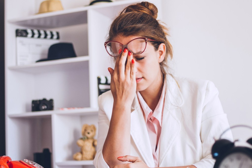 Young and beautiful businesswoman tired from work in the office. Migraña, estrés, dolor de cabeza.