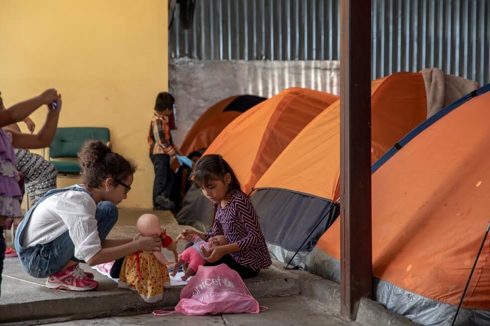 Niños juegan mientras aguardan a que se resuelva su situación migratoria en la frontera con EE. UU. / AFP