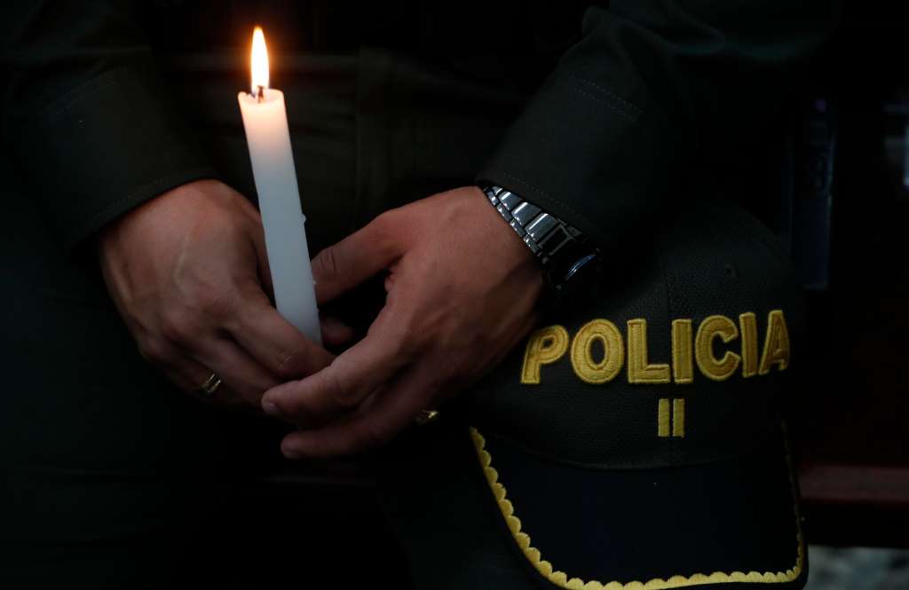 AME5960. CALI (COLOMBIA), 28/07/2022.- Un policía sostiene hoy una vela durante una ceremonia religiosa en honor a sus compañeros asesinados recientemente en el país por el Clan del Golfo, en Cali (Colombia). La Policía colombiana se convirtió en las últimas semanas en blanco de la banda criminal Clan del Golfo, que intensificó los asesinatos selectivos de miembros de la institución en la peor ola de violencia de los últimos cinco años contra dicha institución. EFE/ Ernesto Guzmán Jr