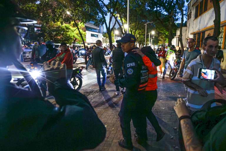 AME6017. CARACAS (VENEZUELA), 28/07/2024.- Agentes intervienen en enfrentamientos entre seguidores del presidente de Venezuela y candidato a la reelección, Nicolás Maduro, con opositores este domingo, en Caracas (Venezuela). Varias decenas de motorizados que se identificaron como chavistas llegaron a un centro de votación en Caracas, donde se encontraban testigos opositores y ciudadanos que esperaban el comienzo del escrutinio de las elecciones presidenciales de este domingo, lo que dio lugar a una confrontación que acabó a golpes, ante la mirada impasible de los policías, que no intervinieron para detener la pelea. EFE/ Henry Chirinos