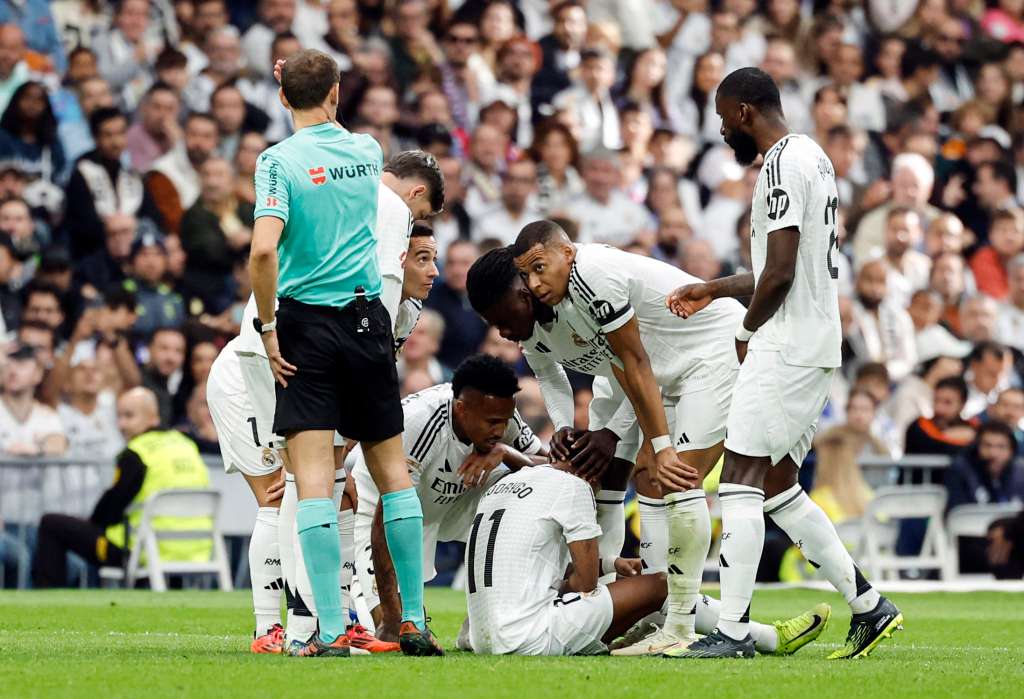 Teammates check on Real Madrid's Brazilian forward #11 Rodrygo after resulting injured during the Spanish league football match between Real Madrid CF and CA Osasuna at the Santiago Bernabeu stadium in Madrid on November 9, 2024. (Photo by OSCAR DEL POZO / AFP)