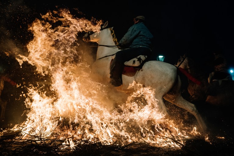 FOTOGALERÍA 3 DE 10.- SAN BARTOLOMÉ DE PINARES (ÁVILA), 16/01/2023.- Un jinete pasa con su caballo por encima de las llamas durante las tradicionales "luminarias" que se celebran hoy lunes en la localidad abulense de San Bartolomé de Pinares. EFE / Raúl Sanchidrián.
