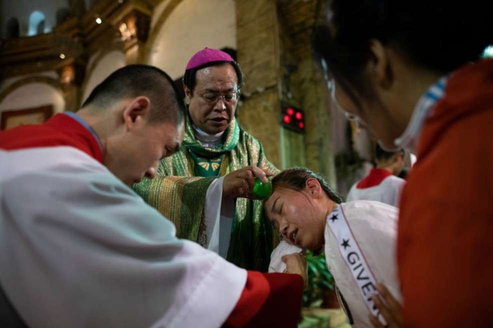 El obispo Joseph Li Shan (C) bautiza a una mujer durante una misa en la Catedral del Sur en Beijing, el 22 de Septiembre. / AFP