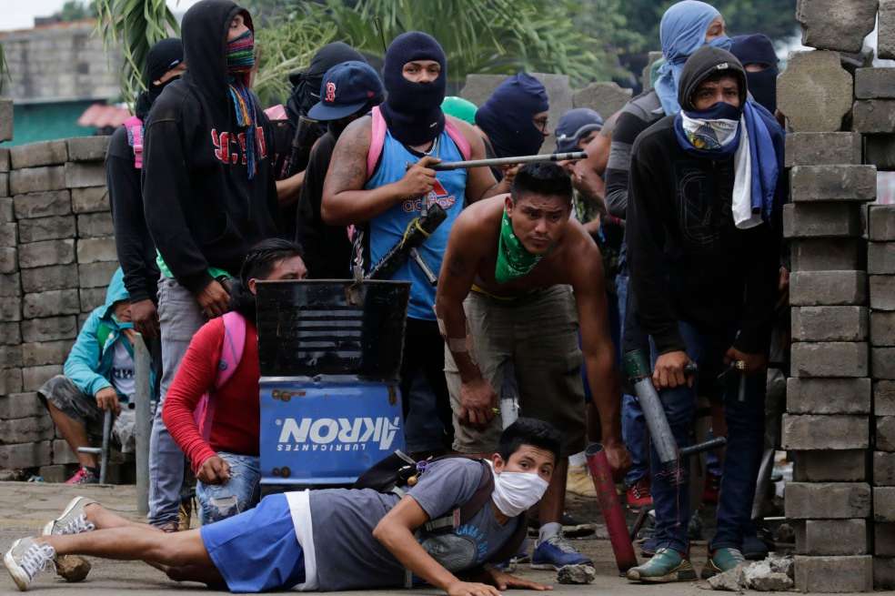 Un grupo de manifestantes en contra de Daniel Ortega se cubren detrás de una barricada en Masaya. / AFP