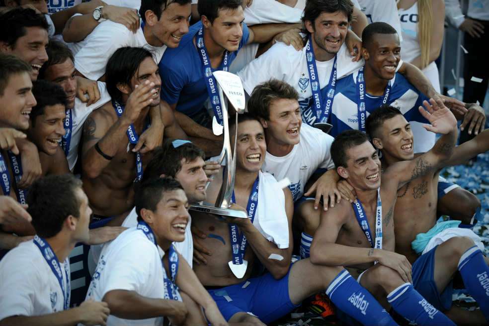 Arriba, a la derecha, el colombiano Jonathan Copete, el domingo en la celebración del título de Vélez. / EFE