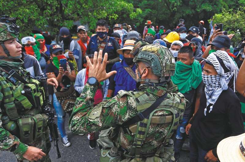 Soldados hablan con indígenas durante una manifestación el domingo en Cali (Colombia). Varias autoridades denunciaron que este domingo supuestos civiles armados disparando contra un grupo de indígenas que estaban manifestándose a las afueras de la ciudad colombiana de Cali, dejando varios heridos. EFE