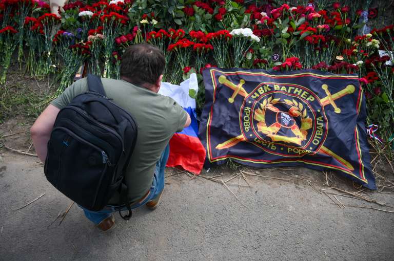 Un hombre lleva flores y bandera al monumento conmemorativo en San Petersburgo.