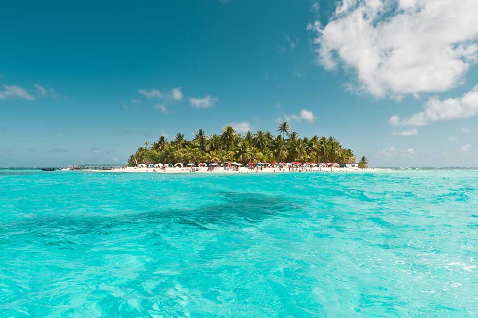 El cayo de Johny Cay visto desde la lancha, con las palmeras, su arena blanca y el mar de un color azul intenso.