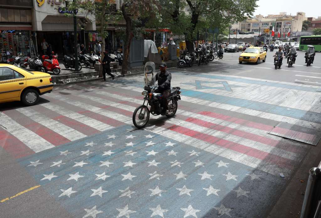 TEHRAN (Iran (Islamic Republic Of)), 04/05/2026.- An Iranian drives over a painting depicting the US and Israeli flags in a street in Tehran, Iran, 04 May 2026. Iranian Foreign Ministry Spokesman Esmaeil Baghaei criticized the US president's plans on the passage of vessels through the Strait of Hormuz, a day after Donald Trump said that Washington would begin escorting ships through the waterway. (Teherán) EFE/EPA/ABEDIN TAHERKENAREH