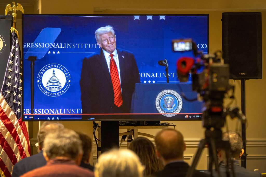 Miembros de los medios de comunicación observan al presidente de EE. UU., Donald J. Trump, pronunciar un discurso en una pantalla de televisión.