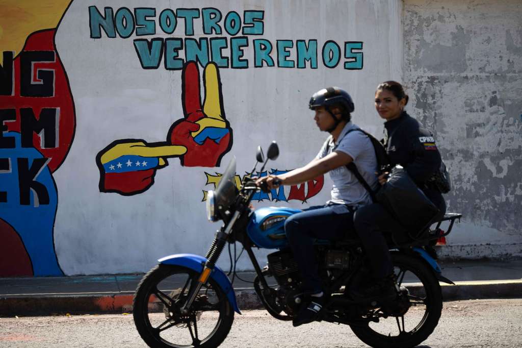 AME9240. CATIA LA MAR (VENEZUELA), 28/01/2026.- Personas en moto transitan frente a un mural del presidente de Venezuela, Nicolás Maduro, este miércoles en Catia La Mar (Venezuela). EFE/Ronald Peña R