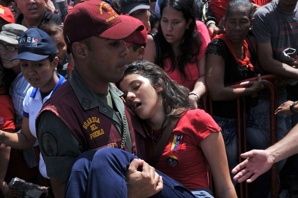 Una mujer desmayada en el intento de ver el féretro de Chávez. / EFE