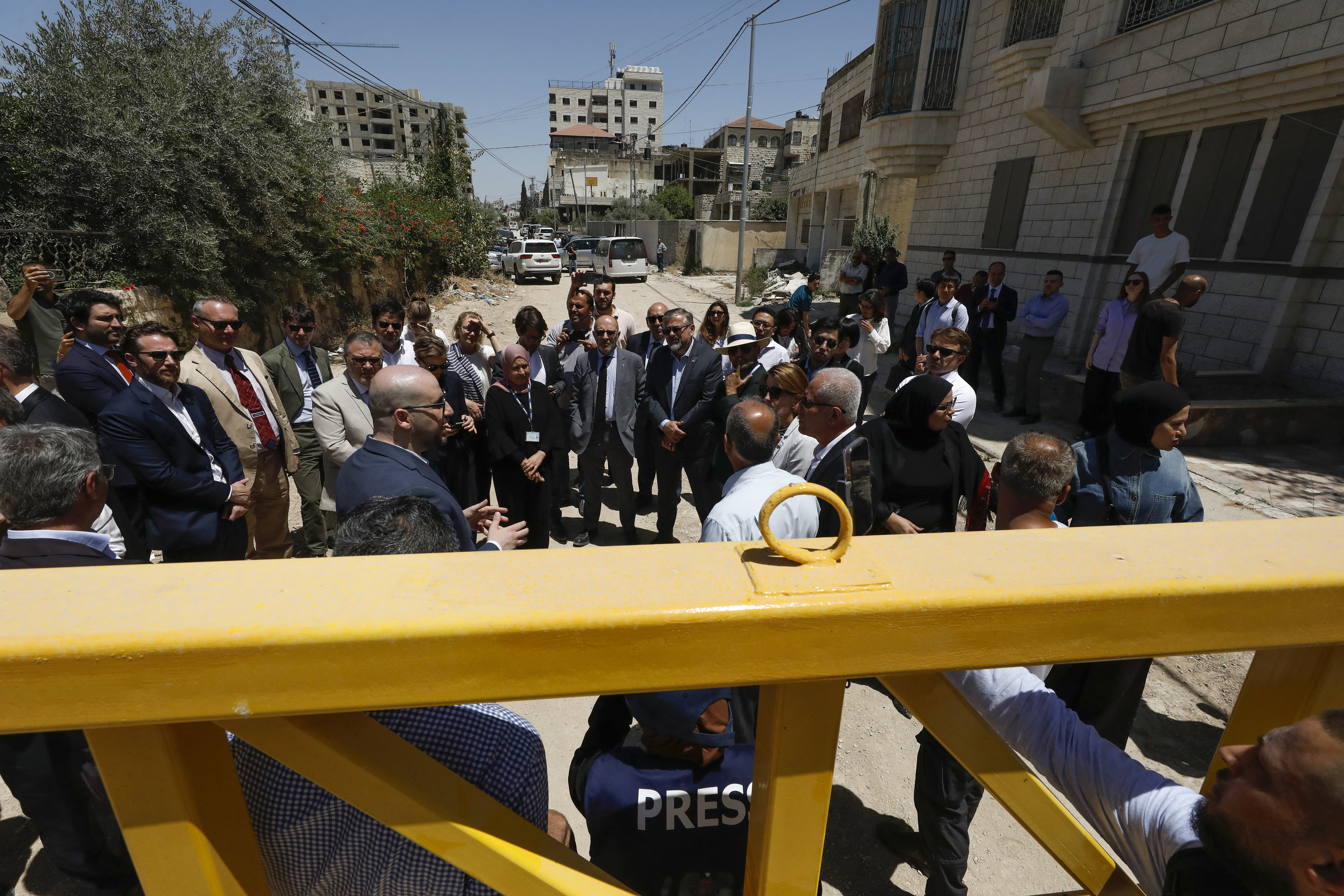 TOPSHOT - Members of a diplomatic delegation from the European Union stand behind a gate on the eastern entrance of Jenin camp during a visit to the city of Jenin, on May 21, 2025, amid an ongoing Israeli military offensive in the occupied West Bank.