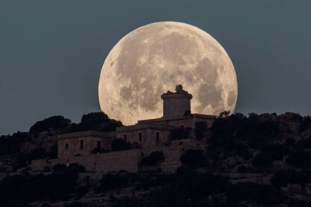 ANDRATX, 17/02/2022.- La conocida como Luna de Nieve, la luna llena de febrero, vista tras el faro Far Vell de Sa Dragonera, también conocido como Na Pòpia , a 360 metros de altura sobre el nivel del mar, anoche en Andratx, Mallorca. EFE/Cati Cladera