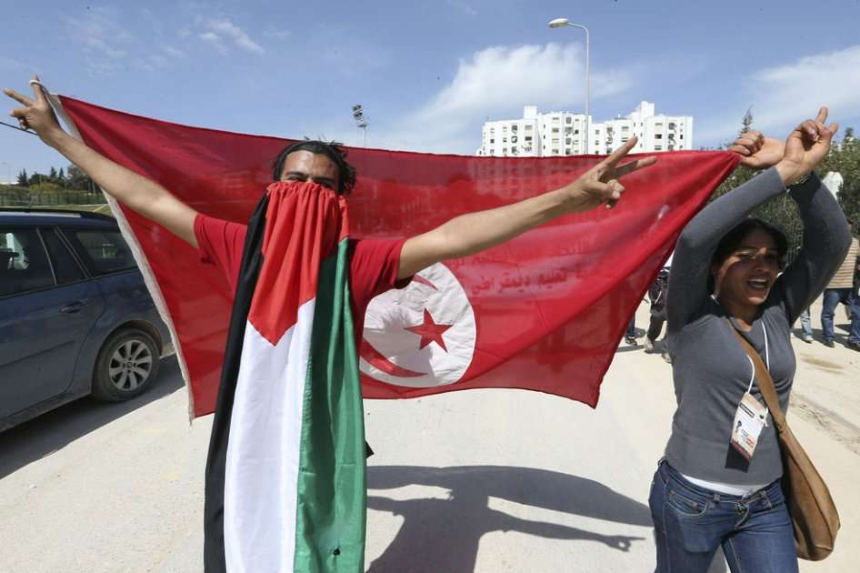 Asistentes al XX Fórum Social Mundial muestran una bandera palestina y otra de Túnez durante la celebración del foro en Túnez