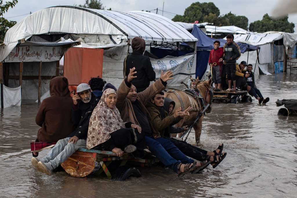 GAZA (-), 11/12/2025.- Displaced Palestinians make their way on animal-drawn carts through a flooded street following heavy rainfall in Khan Younis in southern Gaza, 11 December 2025. According to the Palestinian news agency Wafa, an eight-month-old baby girl died on 11 December due to the extreme cold in Khan Younis, as heavy rain flooded entire camps and areas across the enclave, worsening the conditions for 1.5 million displaced residents. EFE/EPA/HAITHAM IMAD