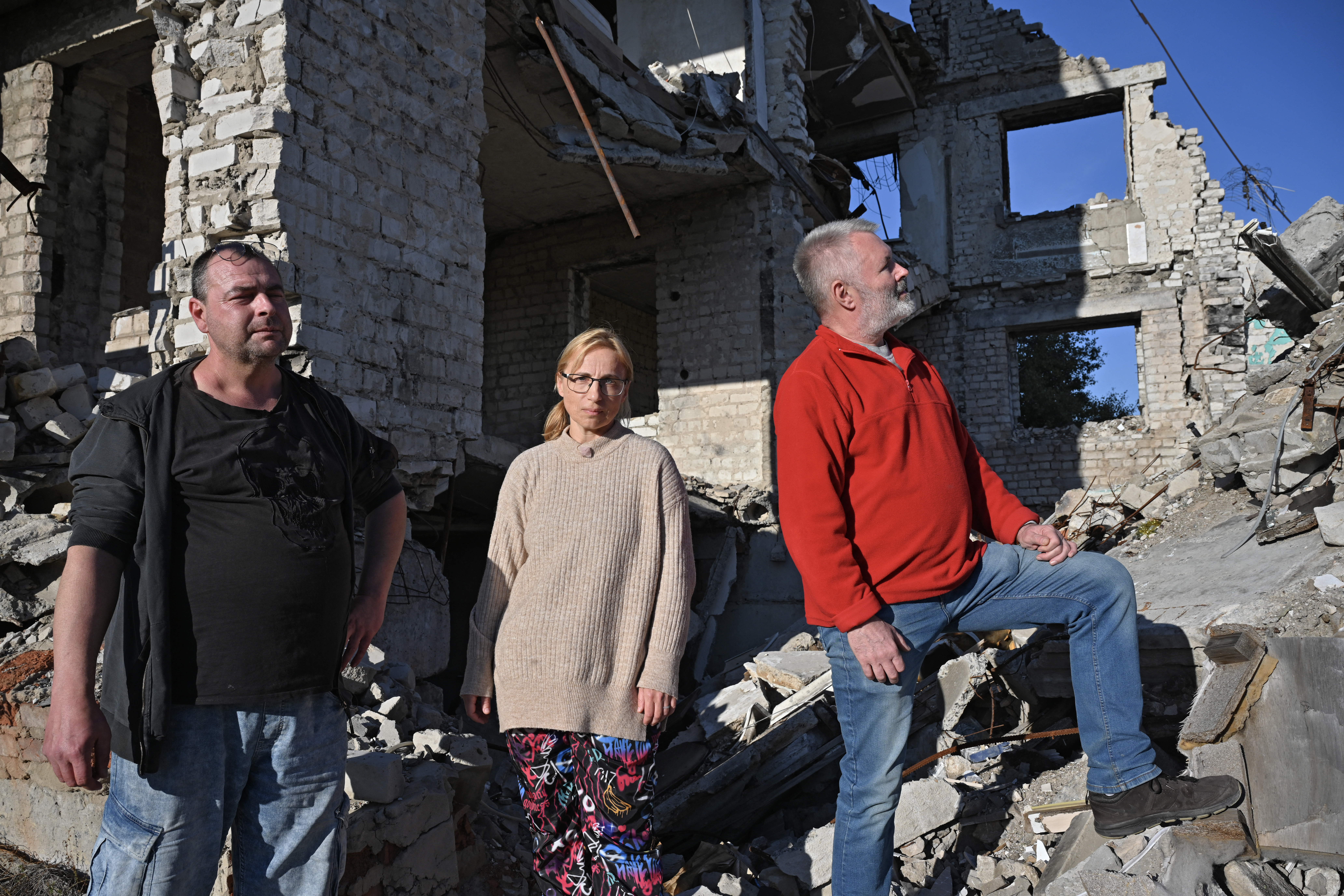 This Handout photo made available by Czech film production company Punk Film shows protagonists of the movie "Great Patriotic Trip" named Nikola (L), Petra (C) and Ivo (R) as they inspect ruins in Izyum, Ukraine on October 22, 2024, during the shooting of a documentary taking three Czechs denying the war in Ukraine to the war zone.