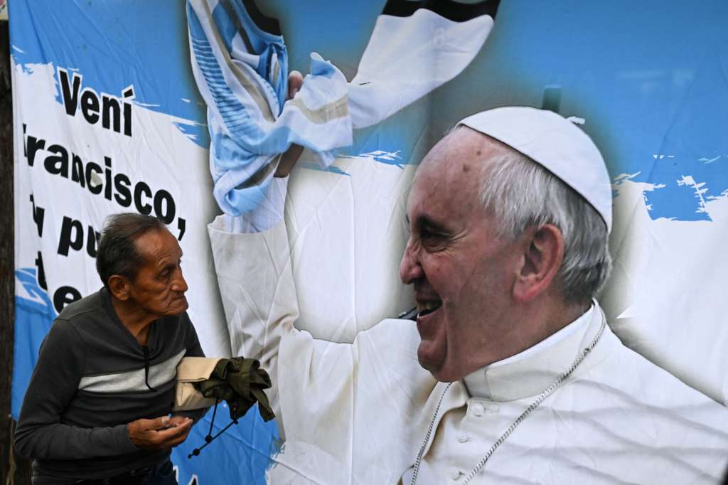 A man walks next to a banner with an image of Pope Francis as he attends a mass for his healing in Constitution Square, the place where, when he was archbishop of Buenos Aires he gave annual masses to denounce exclusion and human trafficking in Buenos Aires, on February 24, 2025.