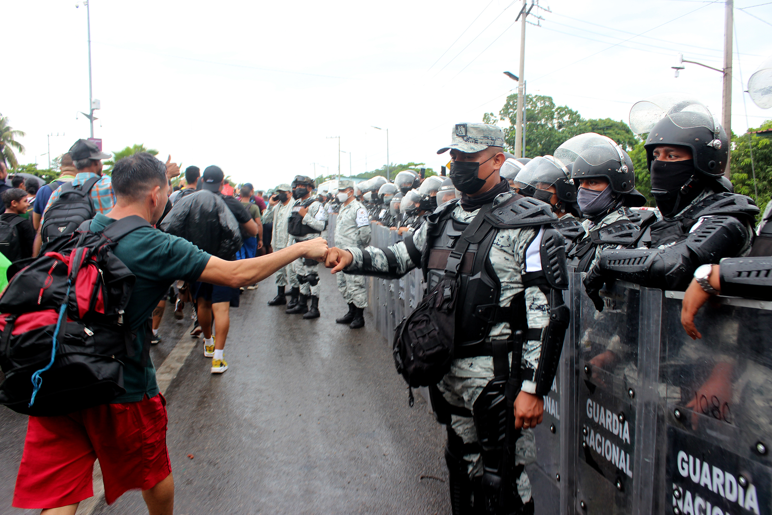 MEX5525. TAPACHULA (MÉXICO), 06/06/2022.- Una persona migrante saluda a un miembro de la Guardia Nacional durante su camino hoy, hacia la frontera norte, en el estado de Chiapas (México). Una inédita caravana de cerca de 15.000 migrantes, la más numerosa hasta ahora, partió este lunes de Chiapas, en la frontera sur de México, rumbo a Estados Unidos, con el trasfondo de la Cumbre de las Américas, que empieza hoy con la migración como prioridad. EFE/ Juan Manuel Blanco