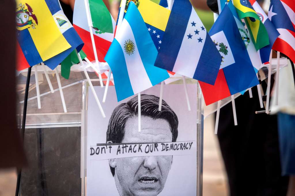 Doral (United States), 20/09/2022.- A picture of the Florida'Äôs Governor Ron DeSantis is seen posted in a podium, under few flags, during a rally and press conference against the relocation of migrants to Martha's Vineyard in Doral, Florida, USA, 20 September 2022. Two flights full of asylum seekers from various countries were sent from Florida to Martha'Äôs Vineyard, Massachusetts, on 14 September 2022 as part of the what the state of Florida called a 'relocation program to transport illegal immigrants to sanctuary destinations'. (Protestas, Estados Unidos) EFE/EPA/CRISTOBAL HERRERA-ULASHKEVICH