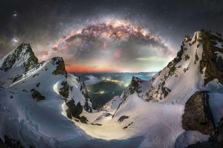 La foto de Tom Rae muestra el arco invernal de la Vía Láctea que se alza sobre la escarpada cordillera Remarkables, en los Alpes del Sur, mientras que las luces de Queenstown, Nueva Zelanda, brillan muy abajo.