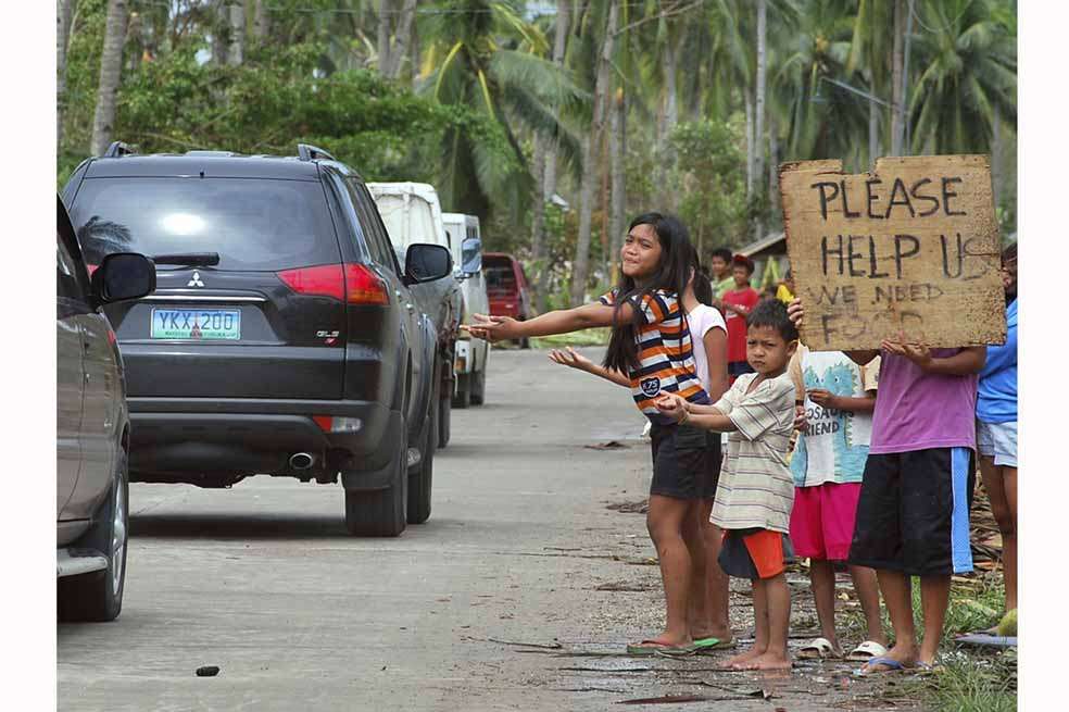 Niños filipinos de la localidad de Borbon piden ayuda en una de las calles luego de que la región fuera azotada por el tifón Haiyan. / EFE