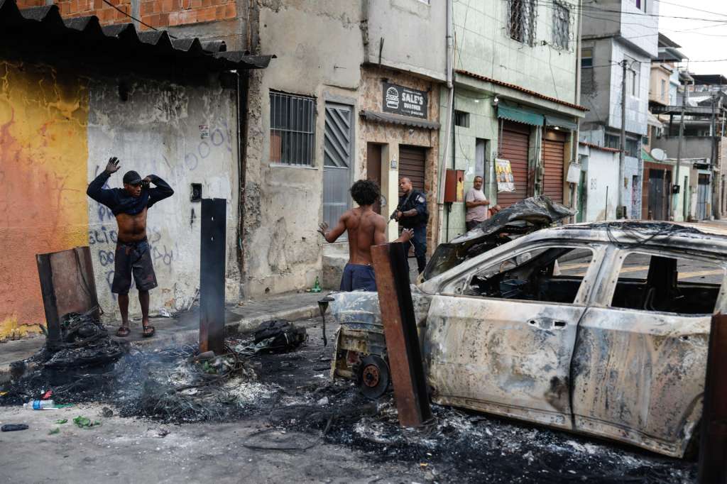 AME2687. RÍO DE JANEIRO (BRASIL), 28/10/2025.- Un integrante de la Policía de Río de Janeiro custodia a dos personas durante un operativo este martes, en Río de Janeiro (Brasil). Río de Janeiro vivió "escenas de guerra" tras un megaoperativo policial contra el Comando Vermelho, una de las más poderosas bandas del crimen organizado en Brasil, en el que murieron al menos 64 personas y 81 fueron detenidas, en la acción más letal en la historia de la ciudad. EFE/ Antonio Lacerda