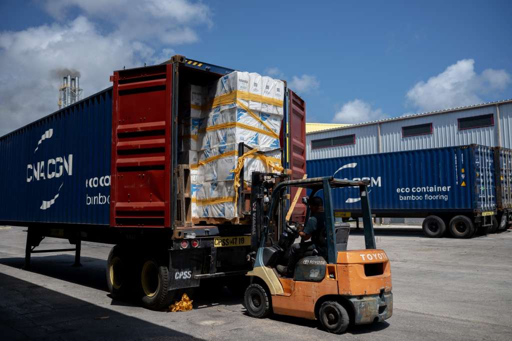(FILES) Workers load boxes into a container at the Harbor Free Economic Zone in Willemstad, Curacao, in the Dutch Caribbean on March 14, 2024.