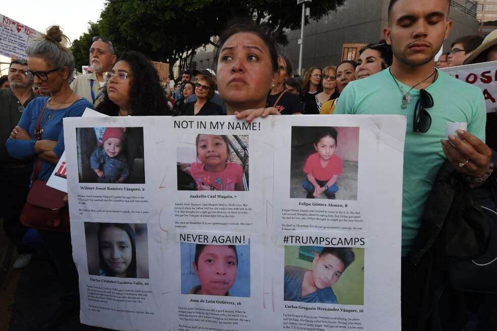 Una mujer sostiene una pancarta con fotos de niños que habrían muerto en centros de custodia en la frontera entre México y Estados Unidos. / AFP