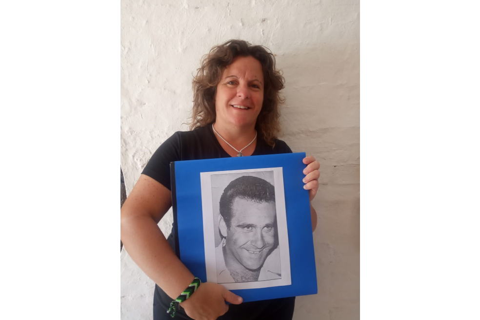 María José Rodríguez, sonriente, sostiene un retrato a blanco y negro de su padre.