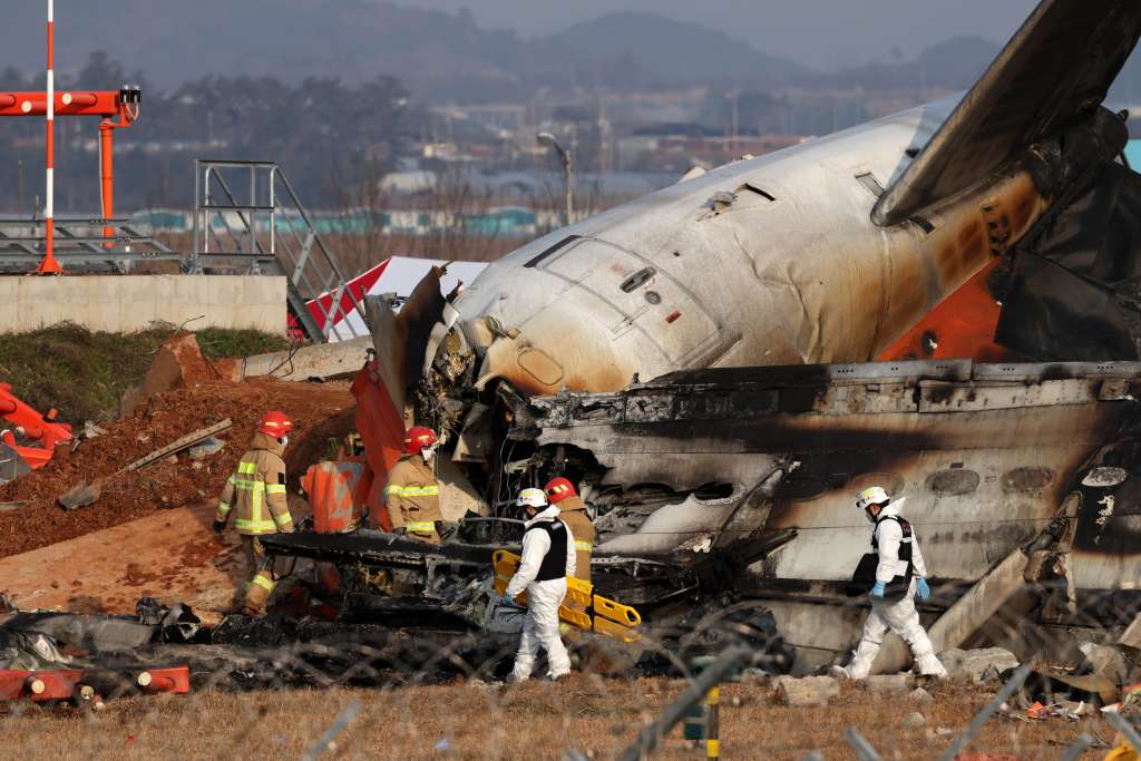 Muan (South Korea), 29/12/2024.- Integrantes del cuerpo del bomberos trabaja en los restos del avión de Jeju Air en el aeropuerto internacional de Muan este domingo, al suroeste de Seúl (Corea del Sur). Según la Agencia Nacional de Bomberos, un avión de pasajeros que transportaba a 181 personas estalló en llamas tras salirse de la pista en un aeropuerto del condado de Muan, al suroeste de Corea del Sur, dejando al menos 176 muertos. EFE/EPA/EFE/ Han Myung-gu