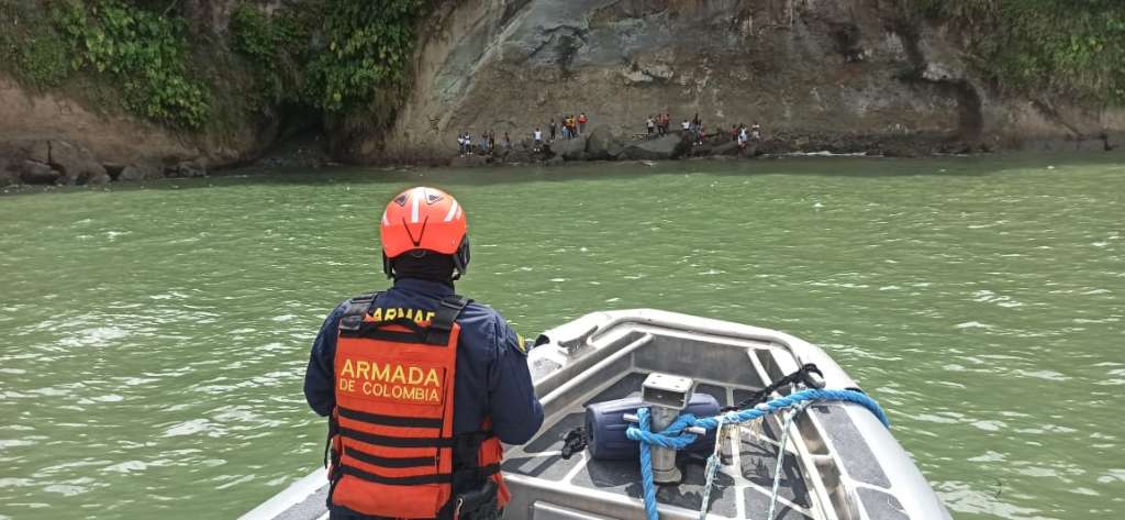 Una lancha avanza hacia una zona rocosa para rescatar a 25 personas que se observan al fondo de la imagen.