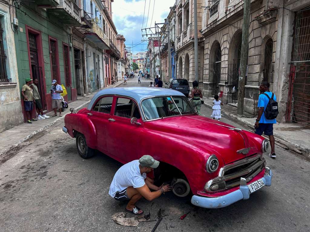 A man repairs an old American car in the middle of the street in Havana on September 3, 2024.