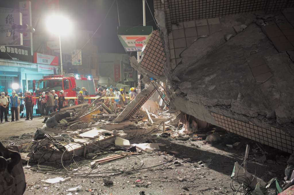 Empleados del gobierno inspeccionan el lugar junto a un edificio derrumbado tras un terremoto en Taiwán.