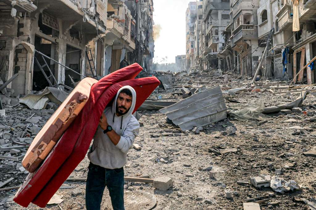 Un hombre camina con colchones entre la destrucción en el campo de refugiados de Jabalia, en la Franja de Gaza.