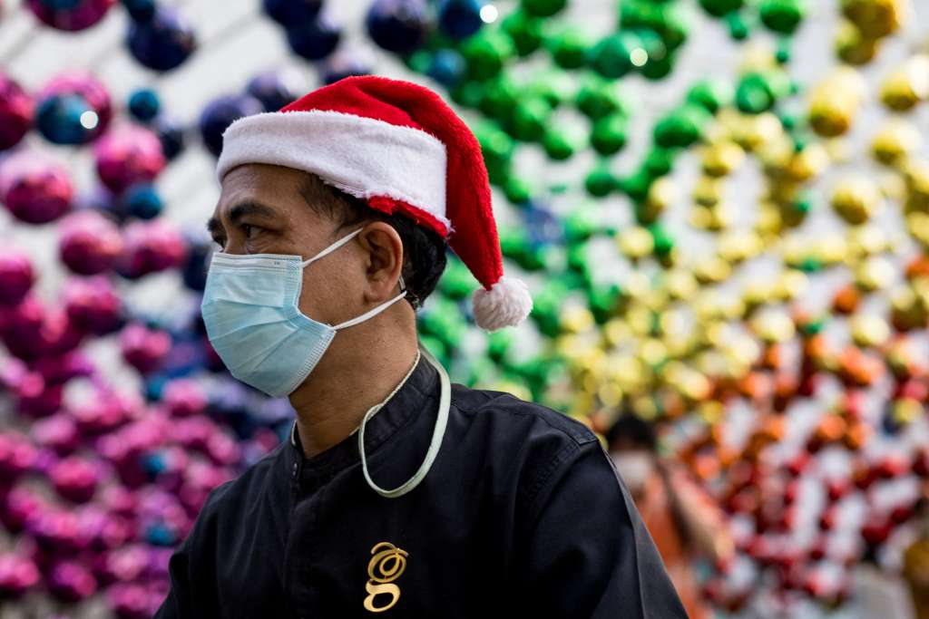 A man wearing a face mask and a Christmas Santa hat walks below decorations outside a shopping mall in Bangkok on December 6, 2021 as Thailand recorded on Monday its first case of the Covid-19 coronavirus Omicron variant. (Photo by Jack TAYLOR / AFP)