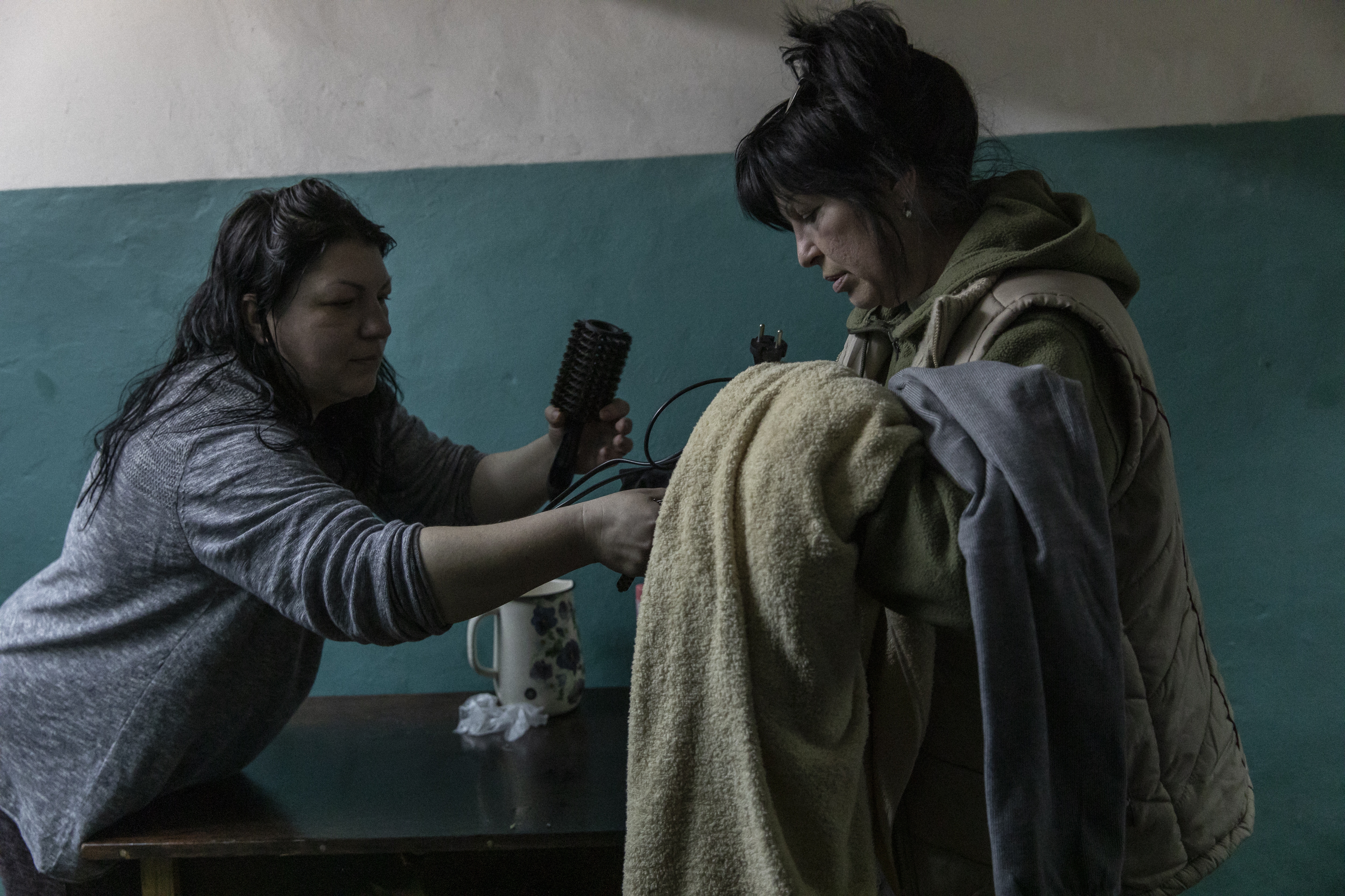 Elena, de 35 años, toma material para lavar el cabello de manos de su madre, en
la estación de metro de Járkov, Ucrania, donde ahora vive.