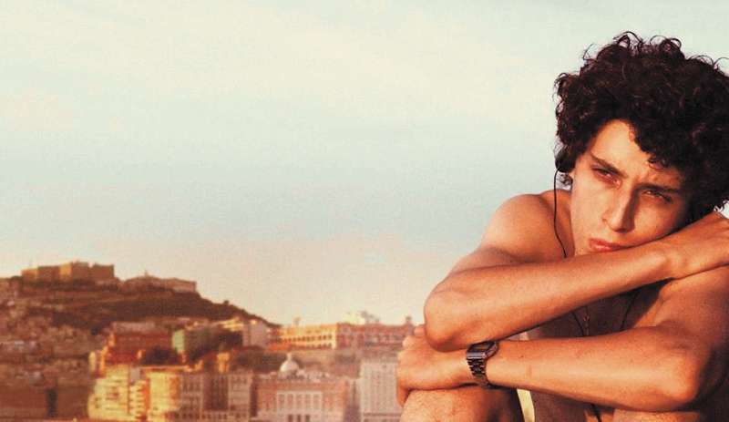 Imagen de la película italiana "Fue la mano de Dios" con Filippo Scotti, el protagonista que encarna a Fabietto Schisa, en primer plano y con la ciudad de Nápoles detrás. / Cortesía: Netflix