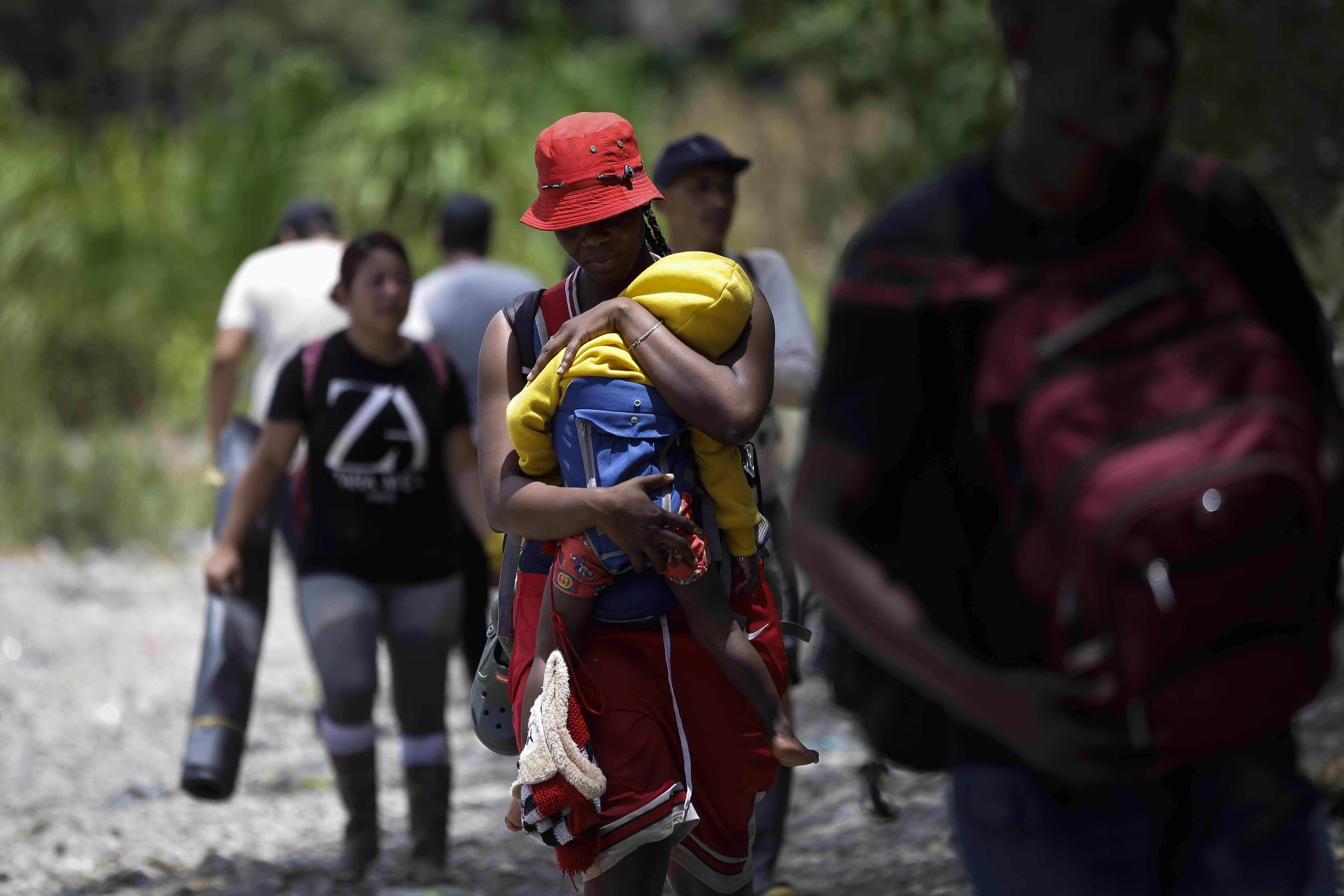 -FOTODELDÍA- AME4250. BAJO CHIQUITO (PANAMÁ), 21/03/2023.- Una persona migrante haitiana carga a su hijo en la selva mientras esperan para ser trasladados en canoa desde la Quebrada León hasta a la comunidad de Bajo Chiquito, el 10 de marzo de 2023, en Darién (Panamá). "Guerreros", repiten las madres, hijos guerreros que han aguantado largas caminatas, hambre, sed, el calor, picaduras de insectos, superar ríos y cerros, para sobrevivir a la selva del Darién en su ruta hacia Estados Unidos. Recién salidos de esta selva que hace de frontera natural entre Colombia y Panamá, los migrantes llegan hasta la conocida como Quebrada del León, donde les esperan unas piraguas de indígenas que los descenderán por el casi seco río Tuquesa hasta Bajo Chiquito, una pequeña población emberá donde podrán al fin reposar tranquilos. EFE/ Bienvenido Velasco