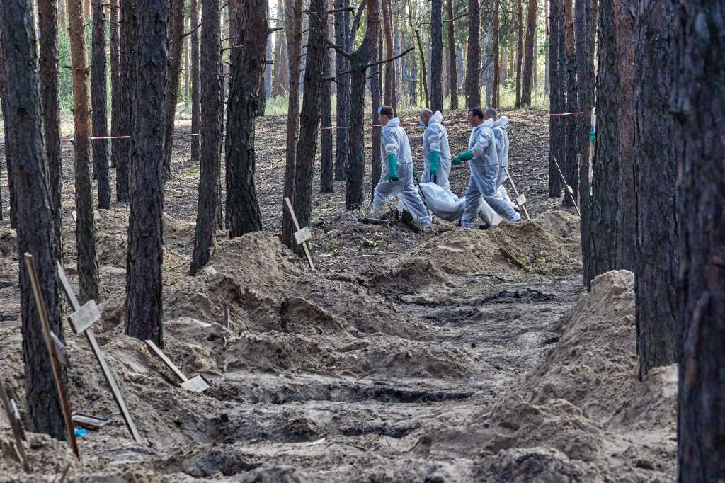 Izyum (Ukraine), 19/09/2022.- Ukrainian workers carry a body that was unearthed from graves in Izyum, Kharkiv region, northeastern Ukraine, 19 September 2022. A mass burial site was found after Ukrainian troops recaptured the town of Izyum. According to the head of the investigative department of the police of the Kharkiv region, the burial site, one of the largest in a recaptured city so far, counts more than 440 separate graves. The Ukrainian army pushed Russian troops from occupied territory in the northeast of the country in a counterattack. Kharkiv and surrounding areas have been the target of heavy shelling since February 2022, when Russian troops entered Ukraine starting a conflict that has provoked destruction and a humanitarian crisis. (Atentado, Rusia, Ucrania) EFE/EPA/SERGEY KOZLOV