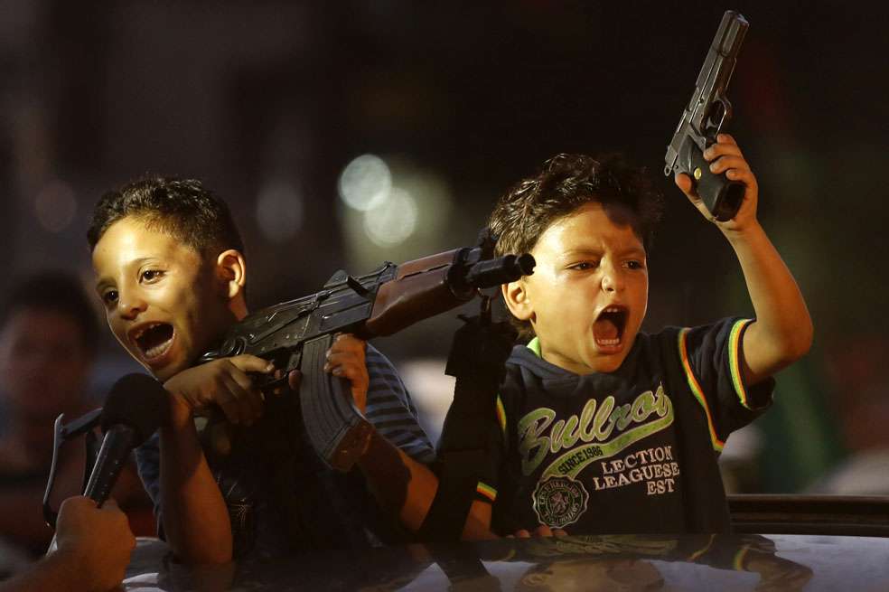 Niños palestinos sostienen armas en medio de la celebración del anuncio de la tregua en Gaza. / AFP
