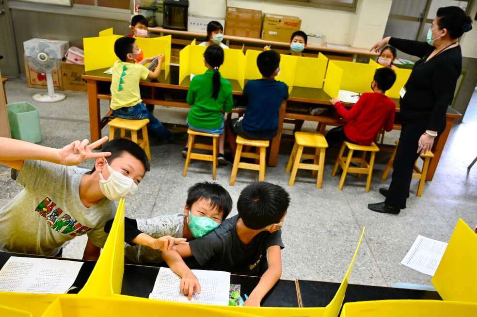 Alumnos separados por divisiones en las escuelas de Taiwán, que intentan retomar la normalidad con el regreso a clases.  / AFP
