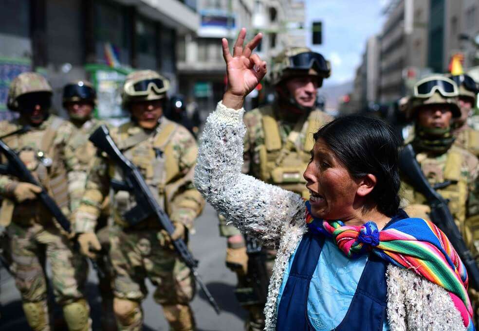 Una mujer indígena boliviana, partidaria del ex presidente boliviano Evo Morales, hace un gesto frente a los soldados durante una protesta contra el gobierno interino en La Paz el 15 de noviembre de 2019. / AFP