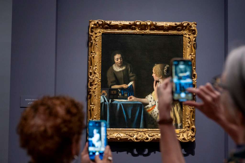 FOTODELDÍA AME6945. NUEVA YORK (ESTADOS UNIDOS), 18/06/2025.- Personas toman fotografías del cuadro "La amante y la criada" durante la muestra "Cartas de amor de Vermeer”, este miércoles en el museo Frick Collection en New York (EE.UU.). La presentación reúne tres cuadros del maestro holandés en los que señoras y sirvientas, retratadas en sus hogares, comparten los secretos de unas misivas aparentemente románticas. EFE/Ángel Colmenares