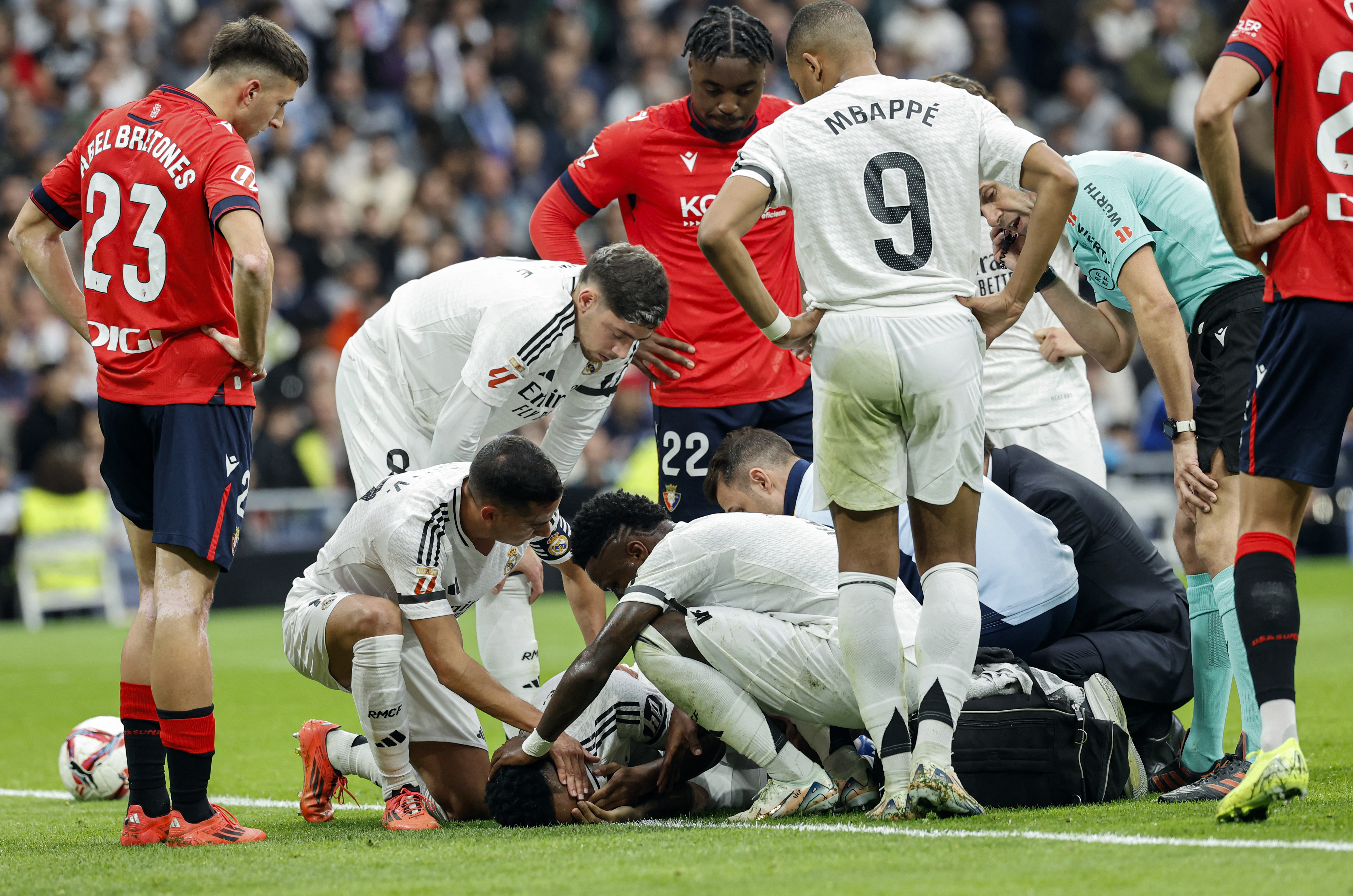 Teammates check on Real Madrid's Brazilian defender #03 Eder Militao (BOTTOM) after resulting injured during the Spanish league football match between Real Madrid CF and CA Osasuna at the Santiago Bernabeu stadium in Madrid on November 9, 2024. (Photo by OSCAR DEL POZO / AFP)