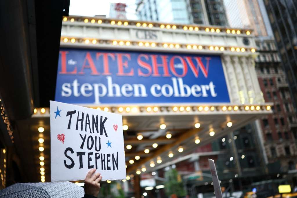 TOPSHOT - People hold signs supporting Stephen Colbert outside the Ed Sullivan Theater ahead of the taping of the final episode of the "The Late Show" after 32 years on air, in New York, on May 21, 2026.