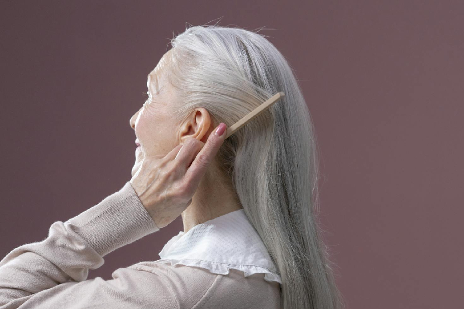 Adulta mayor peinando su cabello con canas